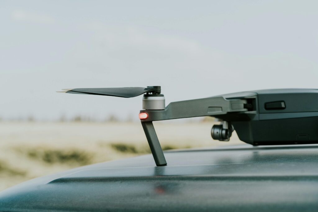 A detailed view of a drone resting on a car roof in a summer outdoor setting.